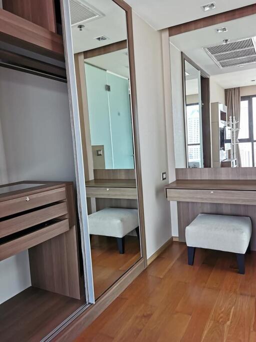 Closet area with wooden furniture, mirror, and small stool