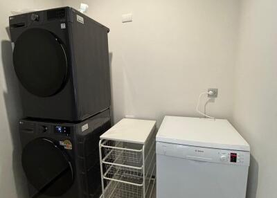 Laundry room with stacked washer and dryer, air conditioner unit, and white cabinet