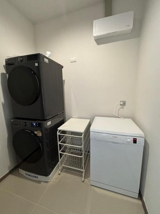 Laundry room with stacked washer and dryer, air conditioner unit, and white cabinet