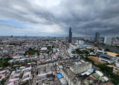 Panoramic view of a city with high-rise buildings and residential areas under a cloudy sky.