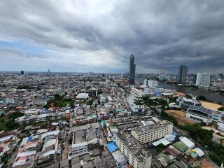 Panoramic view of a city with high-rise buildings and residential areas under a cloudy sky.