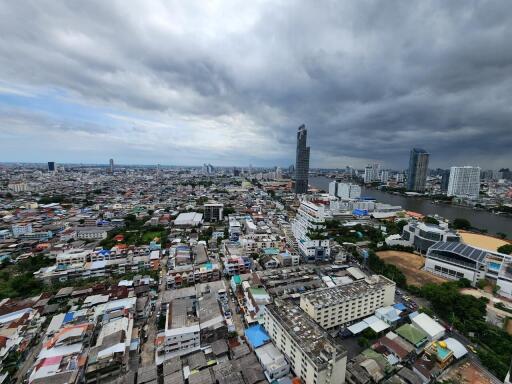 Panoramic view of a city with high-rise buildings and residential areas under a cloudy sky.