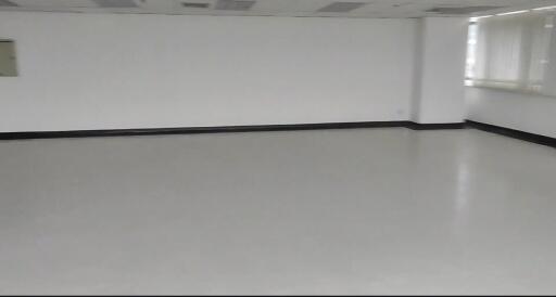 Spacious empty room with white walls and large windows