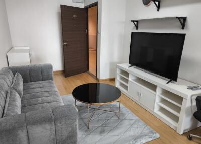 Modern living room with gray sofa, coffee table, and large TV