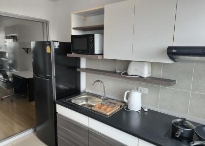 Modern kitchen with black fridge, microwave, sink, and stove