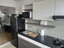 Modern kitchen with black fridge, microwave, sink, and stove