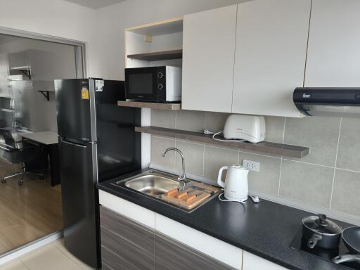 Modern kitchen with black fridge, microwave, sink, and stove