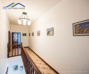 Well-lit hallway with framed artwork and a staircase