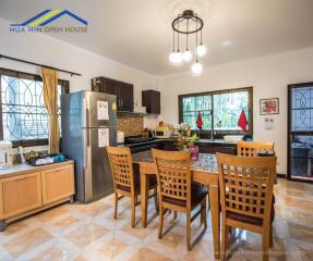 Modern kitchen with wooden dining set, stainless steel appliances, and large windows