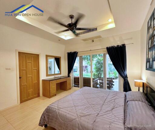 Spacious bedroom with large windows and a ceiling fan