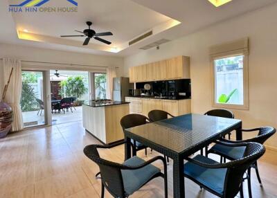 Modern kitchen and dining area with black table and chairs, ceiling fan, and access to outdoor patio