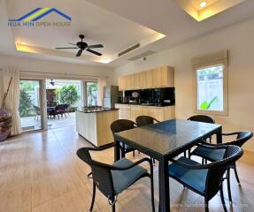 Modern kitchen and dining area with black table and chairs, ceiling fan, and access to outdoor patio