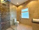 Modern bathroom with glass shower, toilet, and sink