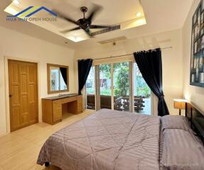 Spacious bedroom with large window, bed, dresser, and ceiling fan