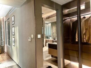 Modern hallway leading to a bathroom with a view of a closet with glass doors