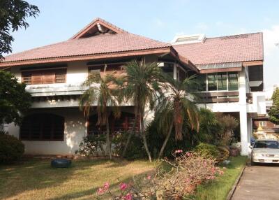 Front view of a large residential house with a well-maintained garden and driveway