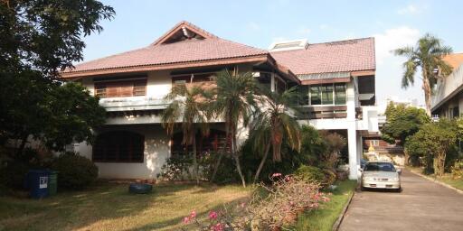 Front view of a large residential house with a well-maintained garden and driveway