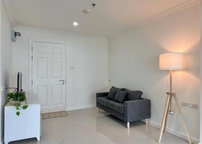 Minimalist living room with grey sofa, white cabinet, and a standing lamp