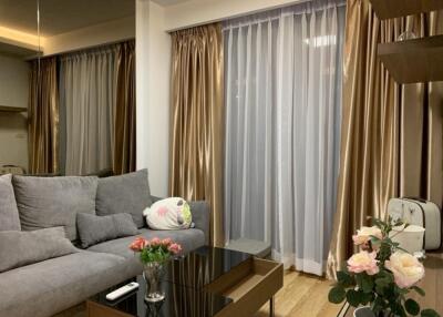 Living room with gray sofa, glass coffee table, and floor-to-ceiling curtains