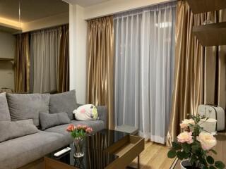 Living room with gray sofa, glass coffee table, and floor-to-ceiling curtains