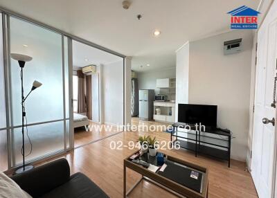 Modern living area with open plan kitchen and access to bedroom