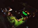 Night aerial view of a well-lit property with pool and garden