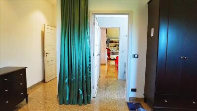 Bedroom with a green curtain leading to an adjacent room