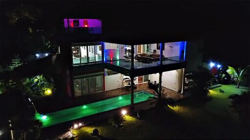 Night view of a modern multi-level glass house with surrounding garden