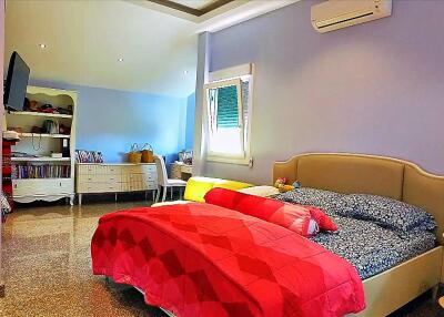 Spacious bedroom with double bed, window, air conditioner, and additional seating area