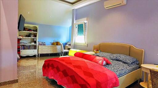 Spacious bedroom with double bed, window, air conditioner, and additional seating area