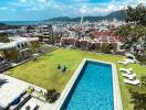 Aerial view of a bright outdoor area with a pool and cityscape in the background