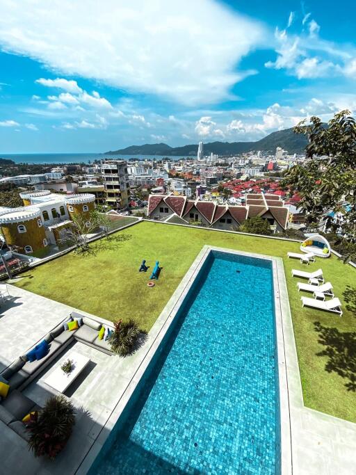 Aerial view of a bright outdoor area with a pool and cityscape in the background