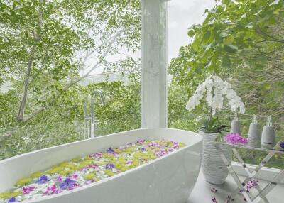 Luxurious bathroom with garden view and bathtub filled with flower petals