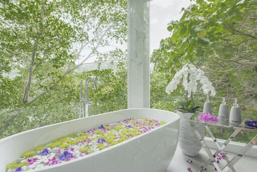 Luxurious bathroom with garden view and bathtub filled with flower petals