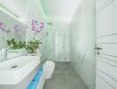 Modern bathroom with marble walls, contemporary fixtures, and decorative plants