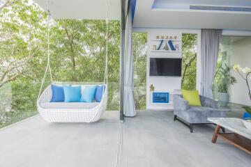 Modern living room with glass wall, swing chair, and lush greenery view