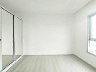 Empty bedroom with mirrored wardrobe and large window