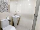 Modern bathroom with mosaic tiled wall and white fixtures