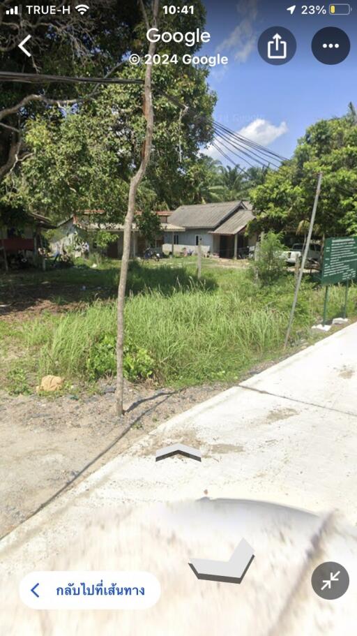 Vacant land with grass and trees, and a house in the background