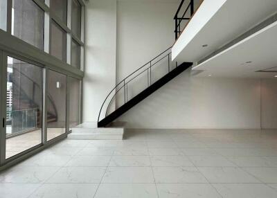 Spacious living room with large windows and a modern staircase