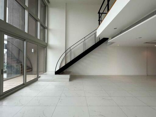 Spacious living room with large windows and a modern staircase