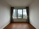 Empty bedroom with large window and city view