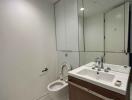 Modern bathroom with white walls, large mirror, and wooden vanity