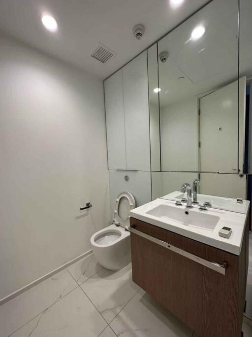 Modern bathroom with white walls, large mirror, and wooden vanity