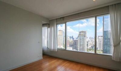 Empty bedroom with a large window and city skyline view