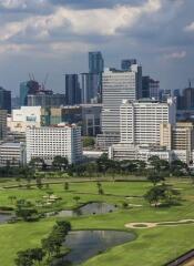 View of city buildings and green park with water features