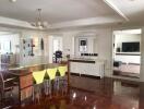 Dining area with wooden floors, modern dining table with green chairs, and adjacent living room with TV