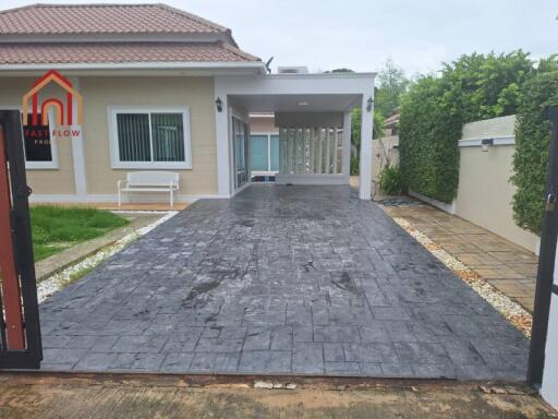 front view of a modern single-story house with a spacious driveway and gated entrance