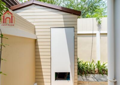 Small backyard storage shed with beige siding and a brown roof.