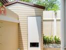 Small backyard storage shed with beige siding and a brown roof.